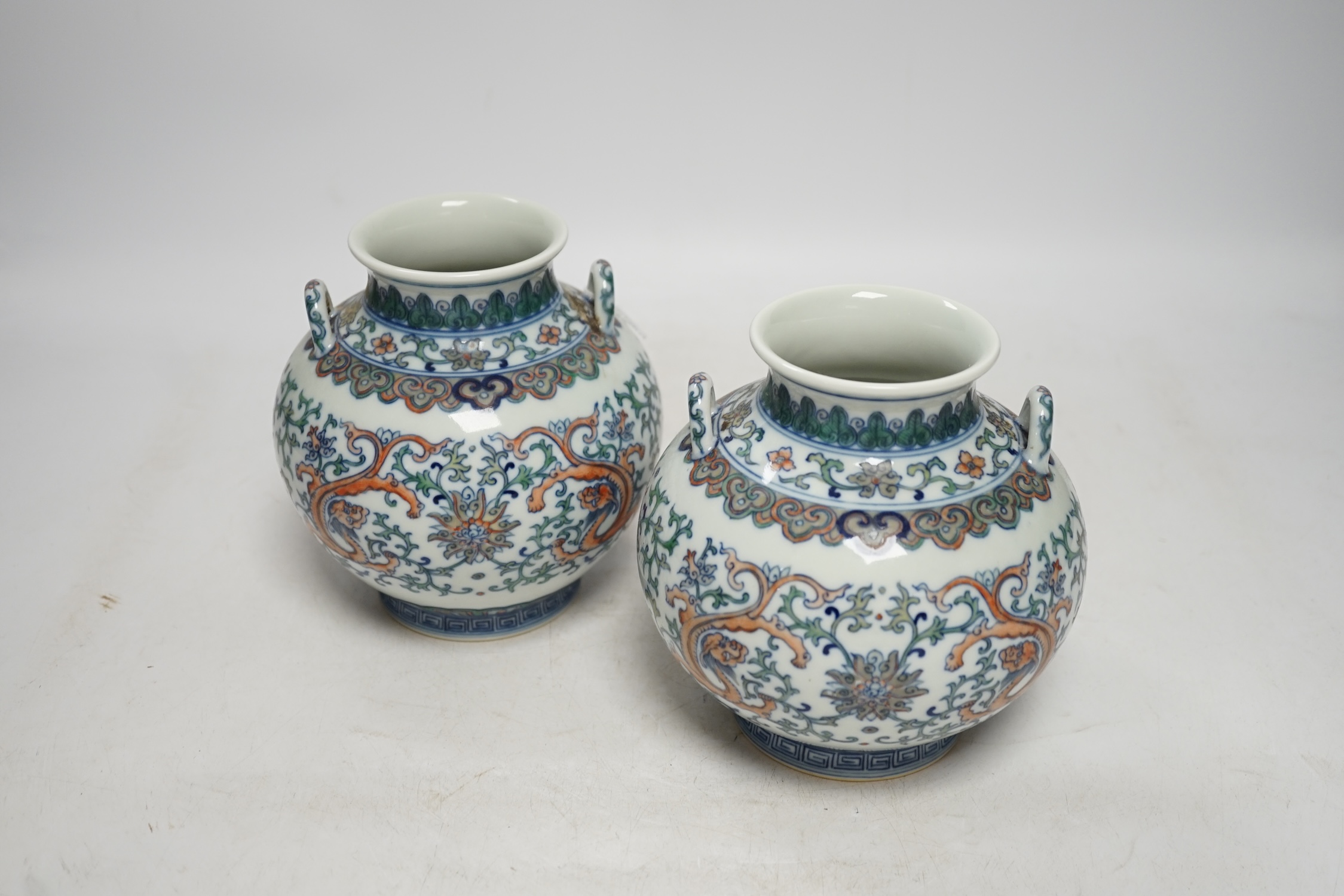 A pair of Chinese porcelain doucai twin handled ‘dragon’ jars, 14cm high. Condition - good